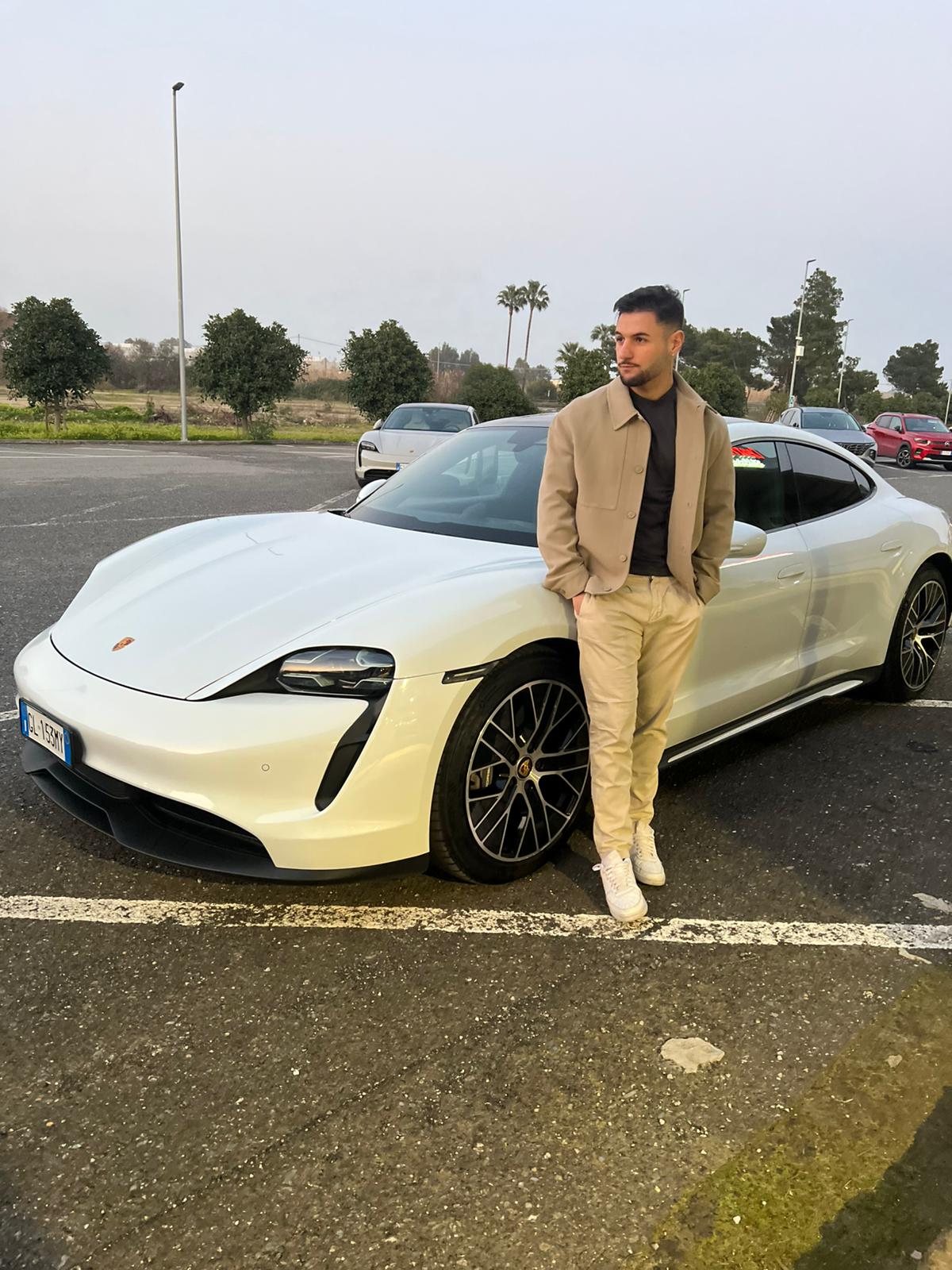 Membro MasterCash al telefono accanto a un'auto sportiva